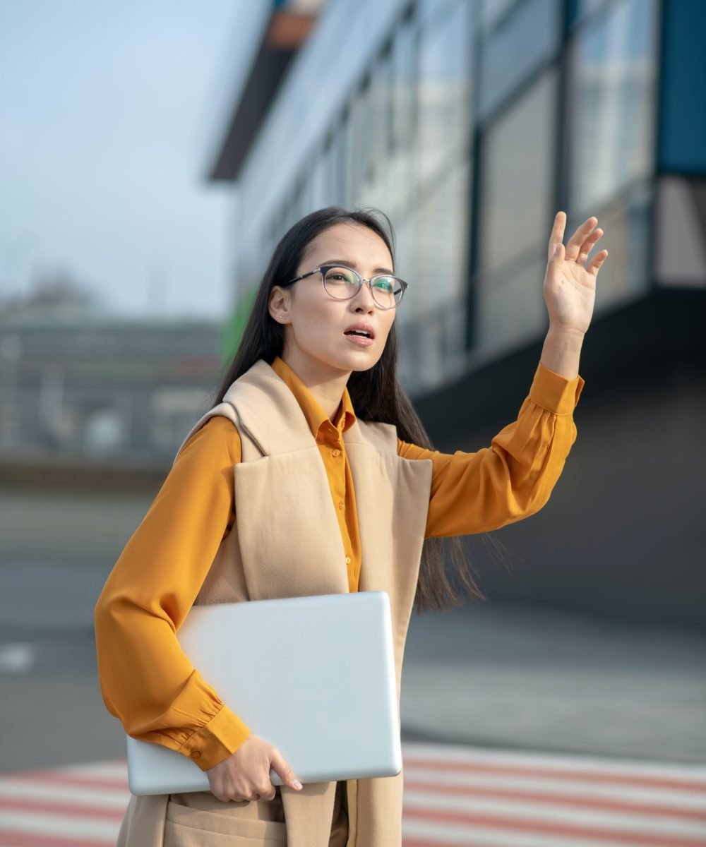 Joven asiática levantando la mano sosteniendo una carpeta